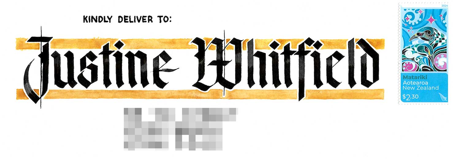An envelope addressed to Justine Whitfield in large black blackletter calligraphy with yellow lines above and below the name.